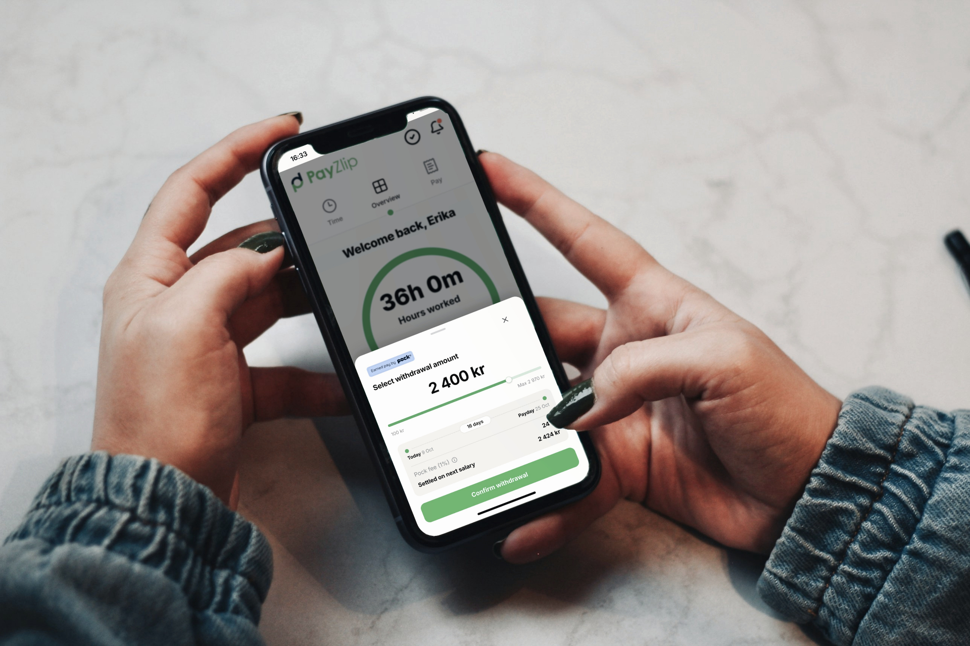 A person confirming an earned pay withdrawal on a phone held over a marble countertop